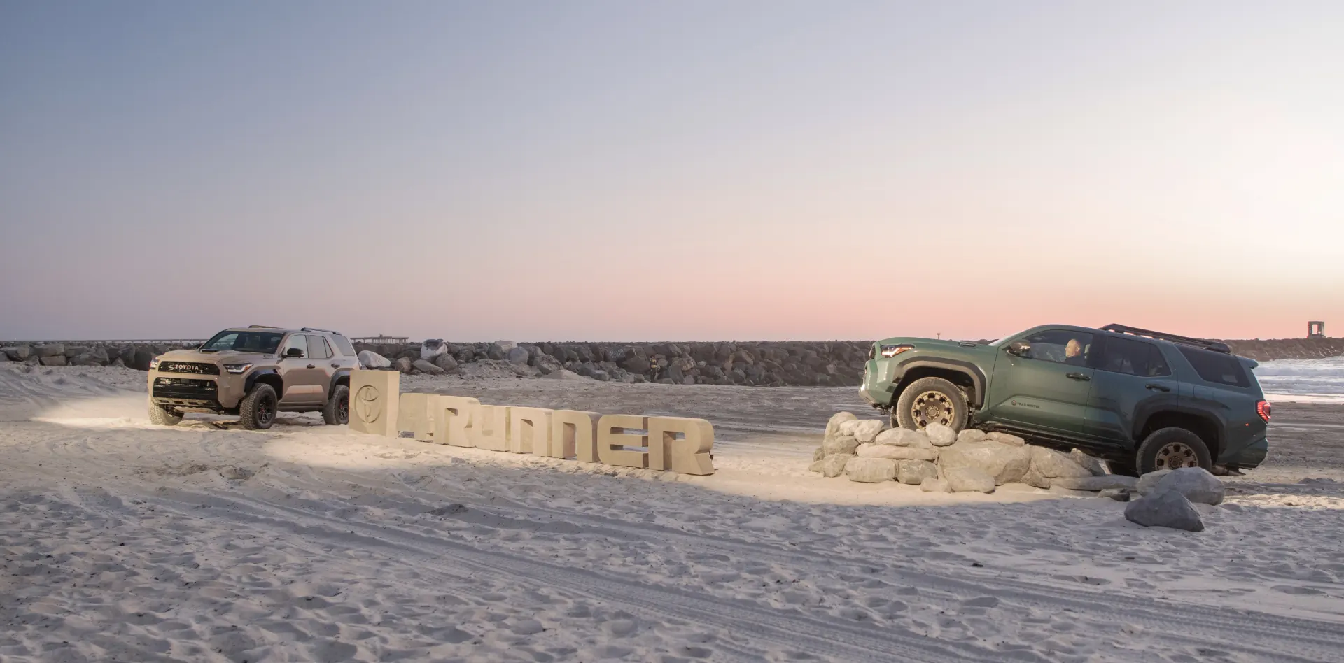 Two Toyota 4Runners displayed on Rock Ramps at the beach reveal